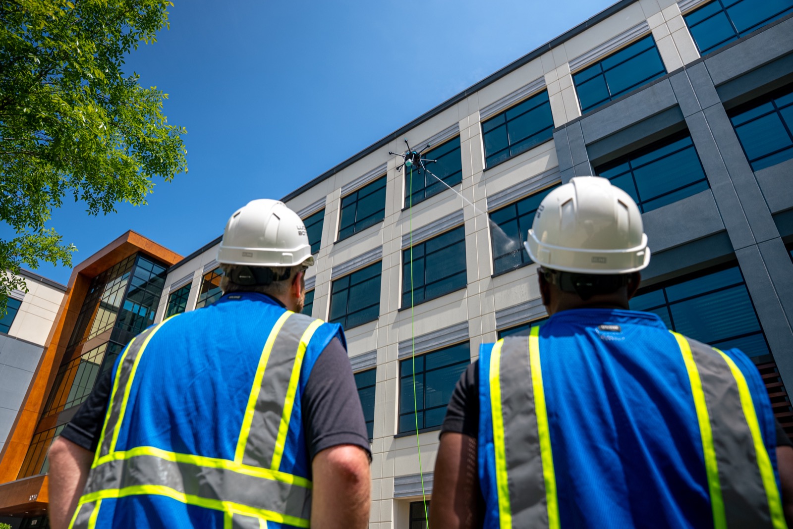 SkyWash Coastal pilots in safety gear operating a cleaning drone on a commercial building